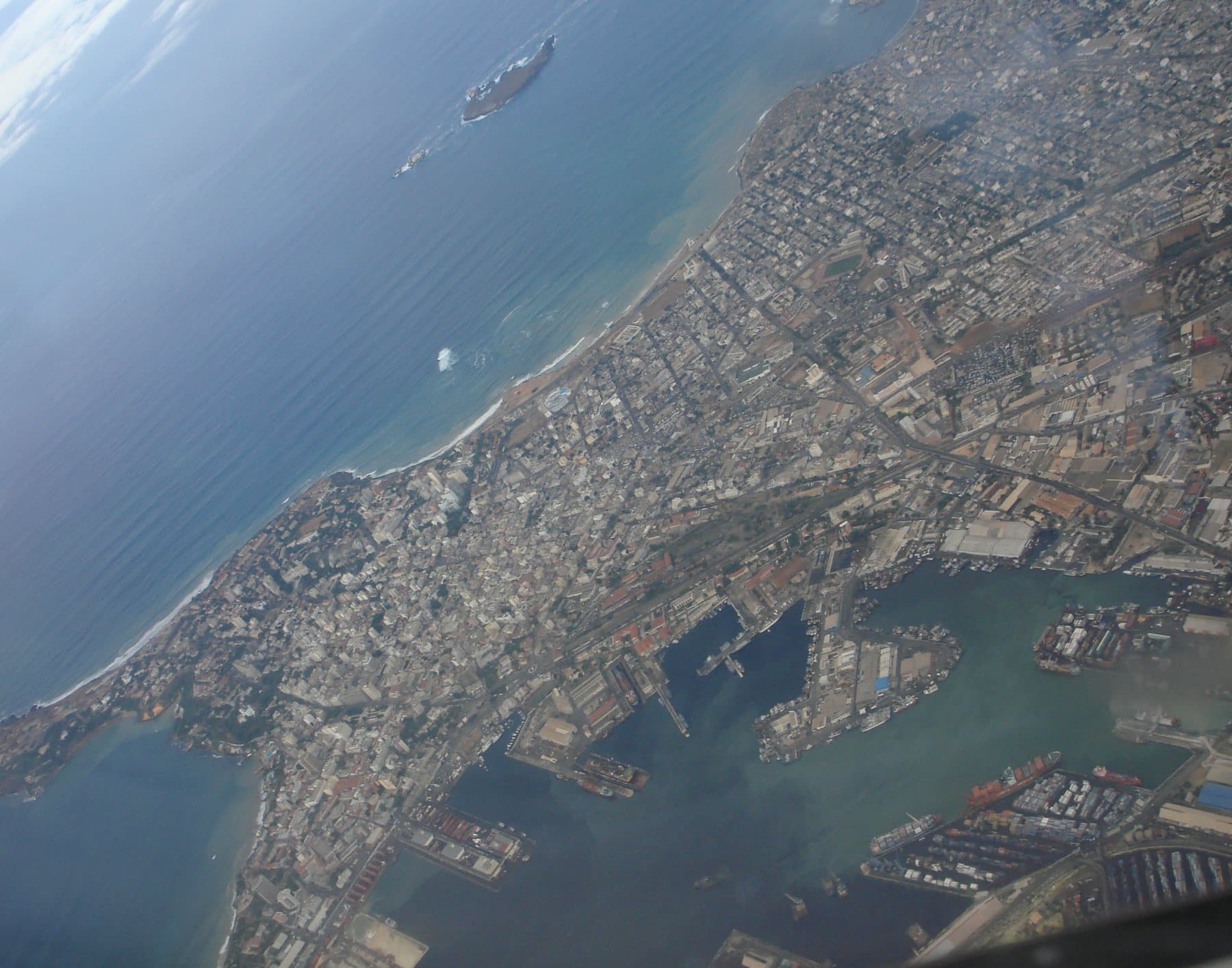 The Dakar peninsula from the air: the city, the Atlantic coastline and the port basins with berthed shipping.